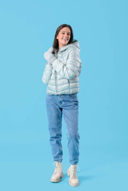 Young woman in winter clothes on blue background