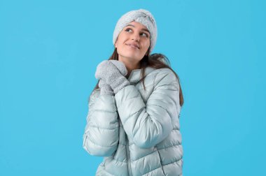 Young woman in winter clothes on blue background