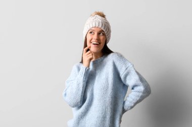 Hafif arka planda kışlık elbiseli genç bir kadın.