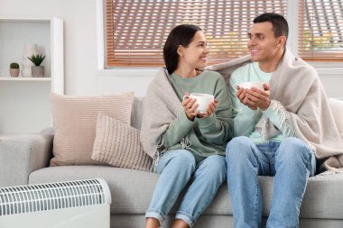 Evde kaloriferin yanında çay ısıtan genç bir çift.