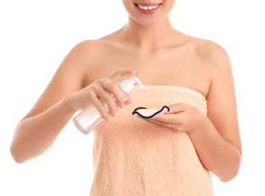 Beyaz arka planda bir şişe mikiler suyu ve yeniden kullanılabilir pamuk pedi olan Asyalı genç bir kadın.