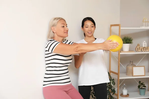 自宅でボールとリハビリテーションセラピストで成熟した女性のトレーニング — ストック写真