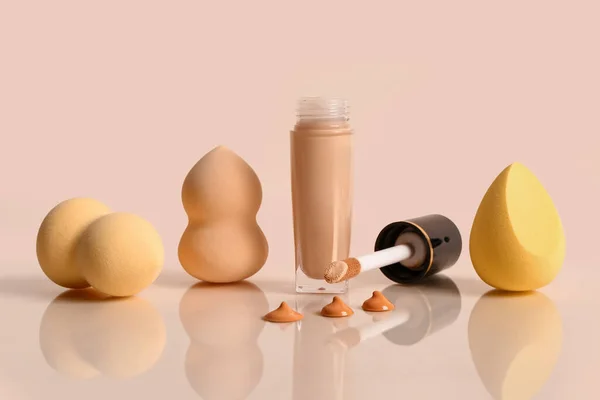 Bottle of makeup foundation and sponges on yellow background