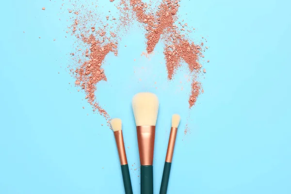 Makeup brushes and highlighter on blue background
