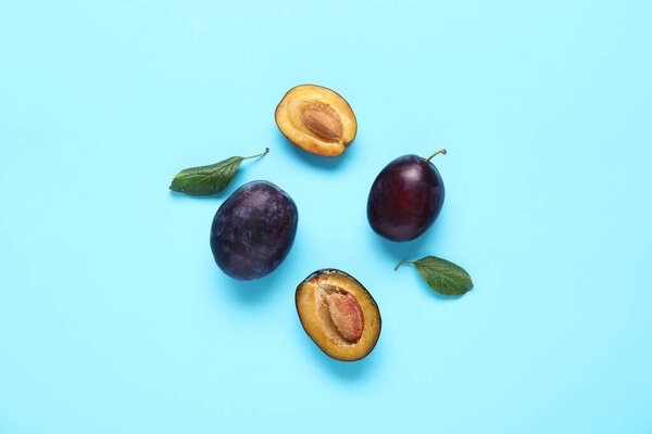 Fresh ripe plums and leaves on blue background