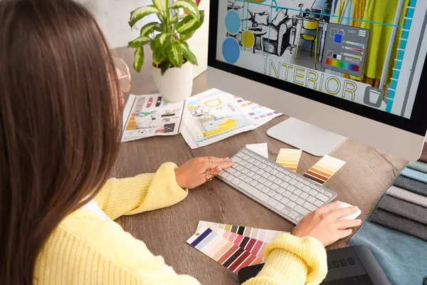Female interior designer working with computer at table in office
