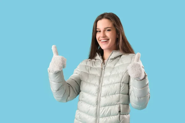 Молода Жінка Зимовому Одязі Показує Великі Пальці Синьому Фоні — стокове фото