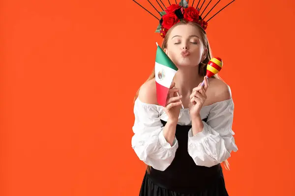 拿着墨西哥国旗和马拉卡的年轻女子在橙色背景下亲吻 — 图库照片
