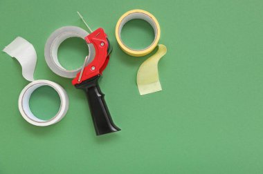 Yapıştırıcı bant ruloları ve yeşil arkaplanda dağıtıcı