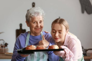 Genç bir kadın ve büyükannesi mutfakta çörek pişiriyorlar.