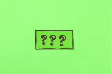 Yeşil arkaplanda soru işaretleri olan sınav kartı