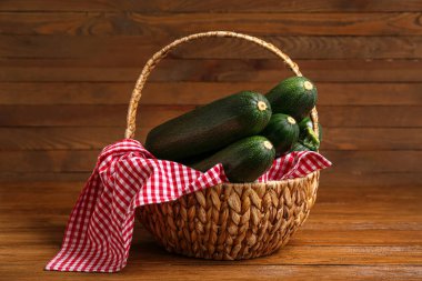 Kahverengi ahşap arka planda taze kabaklı hasır sepet.