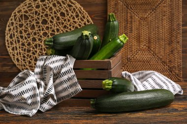 Kahverengi ahşap arka planda taze kabak dolu bir kutu.