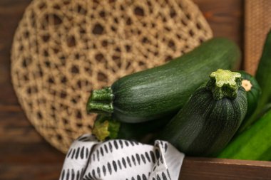 Kahverengi ahşap arka planda taze kabak dolu bir kutu.