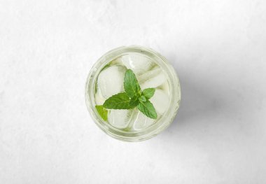 Beyaz arka planda bir bardak taze buzlu nane çayı.