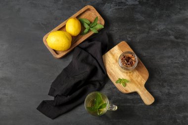 Taze nane çayı, limon ve tarçınlı tahta tahtalar grunge siyah arka planda.