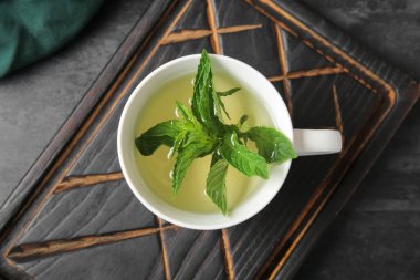 Ahşap tahta üzerinde bir fincan taze nane çayı ile grunge siyah arka planda