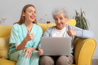 Evde yaşlı bir kadının baş parmağını kaldırdığı bir bakıcı.