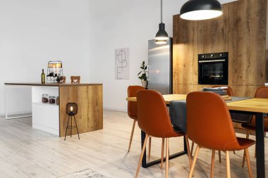 Modern mutfak, yemek masası, ada ve parlayan lambalar.