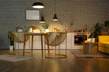 Parlayan lambaları, yemek masası ve akşamları beyaz tezgahları olan modern mutfağın içinde.