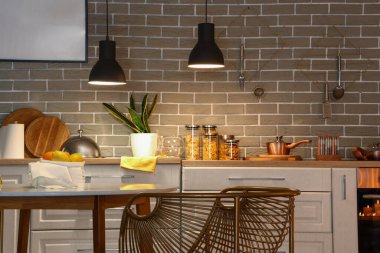 Parlayan lambaları, yemek masası ve akşamları beyaz tezgahları olan modern mutfağın içinde.