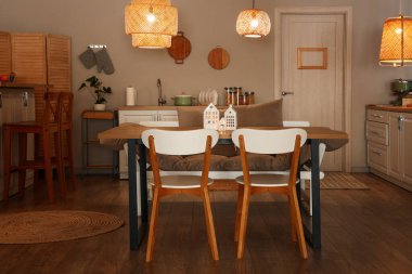 Parlayan lambaları, yemek masası ve akşamları sandalyeleri olan modern mutfağın içinde.