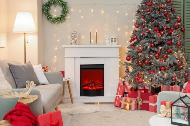 İçinde şömine, gri kanepe ve Noel ağacı olan şenlikli bir oturma odası.