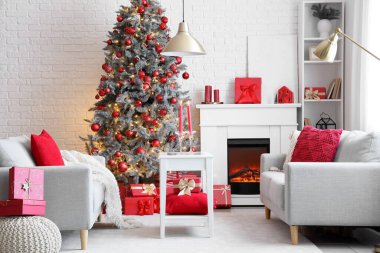 İçinde şömine, Noel ağacı ve kahve masasında yanan mumlar olan festival salonu.