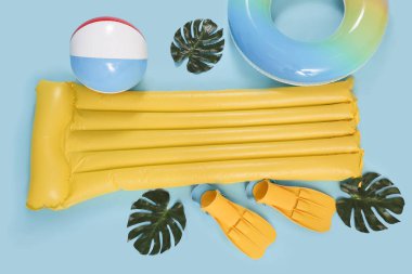 Mavi arka planda plaj aksesuarları olan şişme yatak ve yüzük.