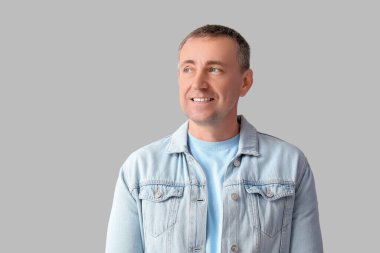 Gri arka planda bir yere bakan düşünceli olgun bir adamın portresi.