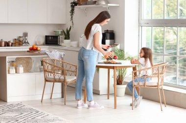 Küçük kızıyla mutlu bir anne mutfakta kahvaltı yapıyor.