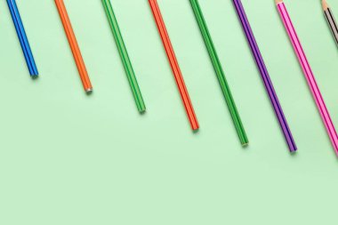 Açık yeşil zemin üzerinde renkli kalemler grubu