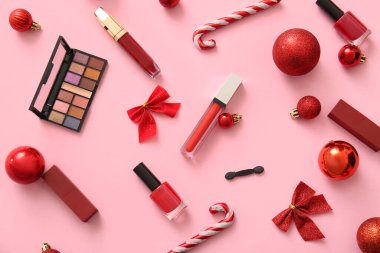 Dekoratif kozmetik ürünleri ve pembe arka planda kırmızı Noel dekoru olan kompozisyon