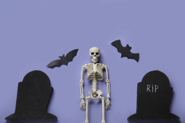 Mavi arka planda Cadılar Bayramı için iskelet, mezar ve kağıt yarasalar kompozisyonu