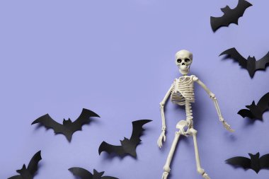 Mavi arka planda Cadılar Bayramı için iskelet ve kağıt yarasalarla kompozisyon