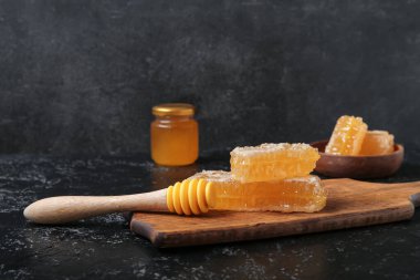 Tahta tahta tahta, tatlı bal petekleri ve koyu arka planda bir kepçe.