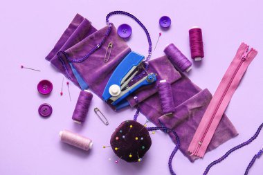 Leylak arka planında farklı malzemelerle elle dikiş makinesi.