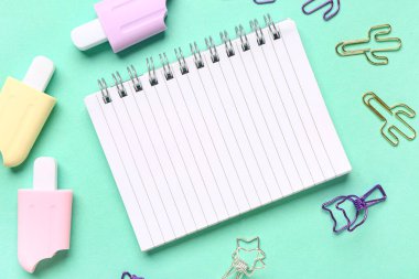 Turkuaz arka planda farklı kırtasiye malzemesi içeren defter
