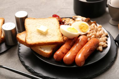 Gri arka planda haşlanmış yumurtalı lezzetli İngiliz kahvaltısı.