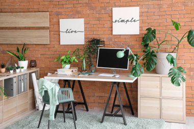 Modern işyeri, raf ünitesi ve ev bitkileriyle şık bir ofis.