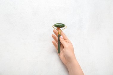 Hafif arka planda taş yüz masajı yapan bir kadın el.