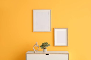 Portakal rengi duvarda boş çerçeveleri olan çekmeceler.