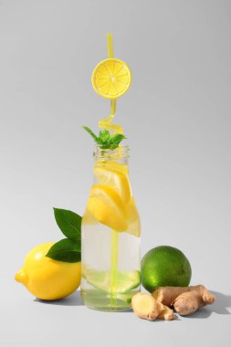 Beyaz arka planda zencefilli ve naneli bir şişe lezzetli limonata.