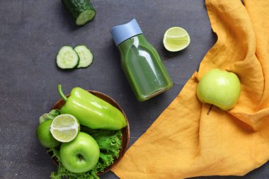 Bir şişe sağlıklı yeşil meyve suyu ve koyu arka planda malzemeler.