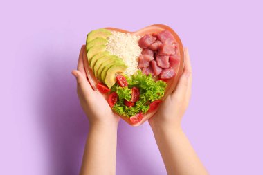 Plakalı kadın eller ve mor arka planda taze sağlıklı ürünler. Diyet kavramı