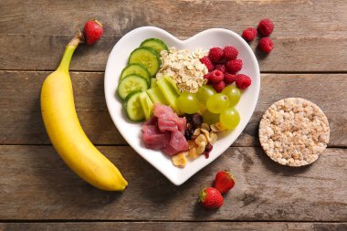 Plate with fresh healthy products on wooden background. Diet concept clipart