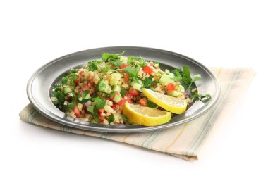 Lezzetli tabakta salata ve beyaz arka planda limon dilimleri.