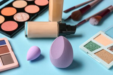 Renkli arka planda makyaj süngerleri ve farklı kozmetikler, yakın plan