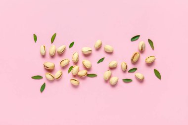 Fıstıklı fıstık ve pembe arka planda yapraklar.