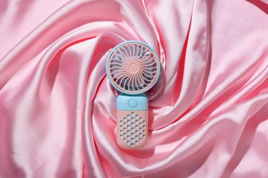 Pembe arkaplanda taşınabilir elektrikli vantilatör.